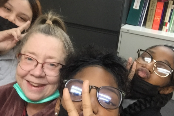 PACE Academy teacher, Mrs. Snyder takes a selfie with three students flashing the “Peace” sign.