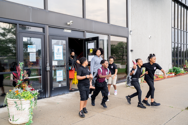 A group of PACE Academy students leave the school building as an adult holds open the door.