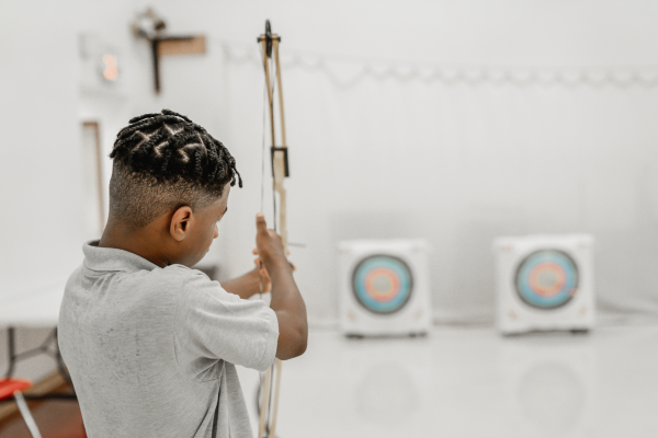 PACE Academy student lines up bow with target during archery class.