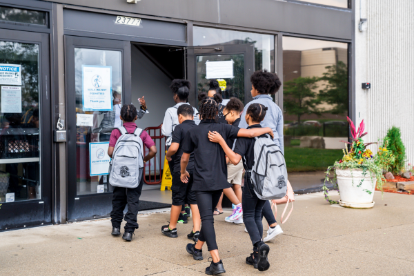 Group of PACE Academy K-8 students are beckoned inside the open door of the school building.