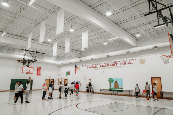 PACE Academy students line up in a large gym space while waiting for a teacher to throw them a basketball.